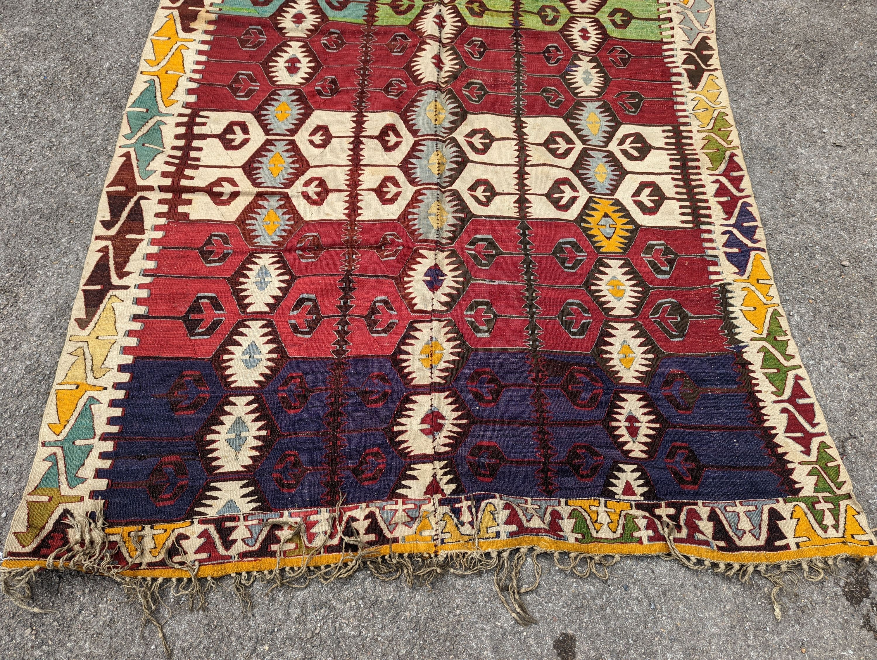 A Kelim polychrome flatweave carpet , cut centrally and re stitched, 425 x 163cm
